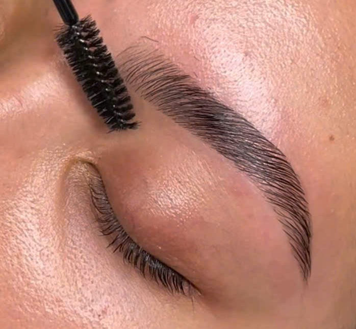 Close-up of a person applying mascara to their eyelashes with a brush.